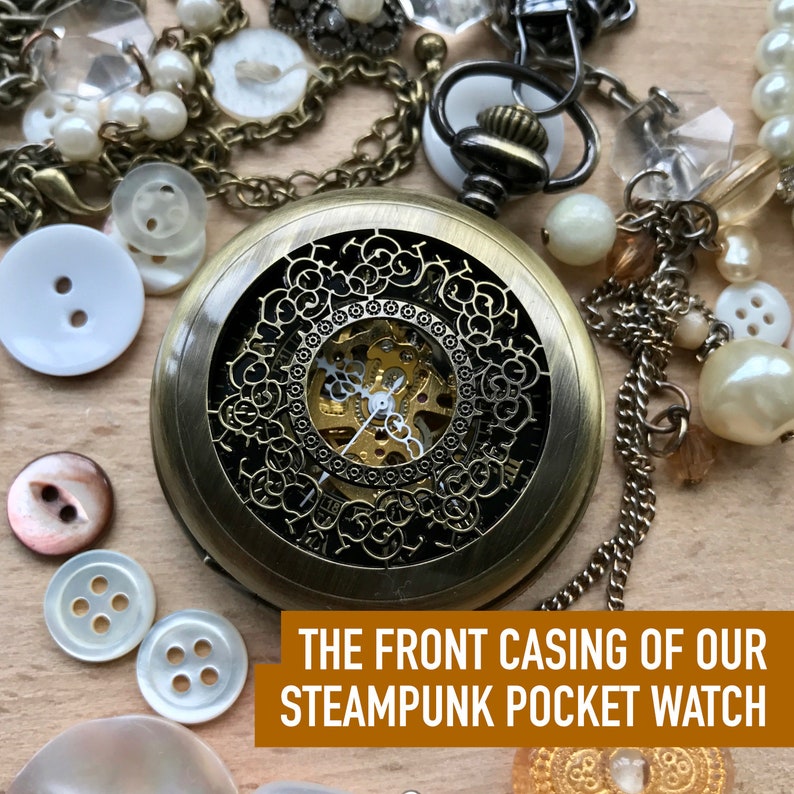 May include: A gold-toned steampunk pocket watch with an intricate, open-faced design. The watch face is visible through the intricate metal casing, revealing the inner workings of the watch.
