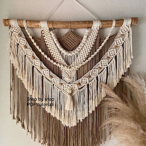 May include: A beige and brown macrame wall hanging with wooden beads and fringe. The hanging is made with a variety of knots and patterns. The text "Step by step PDF tutorial" is visible at the bottom of the hanging.