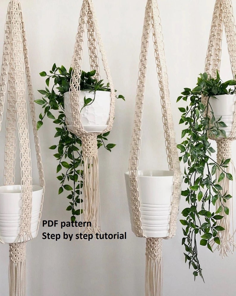 Pu&ograve; includere: Tre portavasi in macram&egrave; con vasi bianchi e piante verdi. I portavasi sono realizzati in corda di cotone naturale e hanno una frangia sul fondo. Il testo "PDF pattern Step by step tutorial" &egrave; visibile nell'immagine.