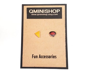 May include: A pair of small, wooden earrings. One earring is shaped like a yellow triangle and the other is shaped like a red bowl. The earrings are displayed on a brown card with the text "Qminishop" and "Fun Accessories".