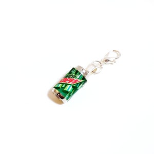 Puede incluir: Un charm plateado con forma de lata de Mountain Dew. El charm tiene un cierre plateado.