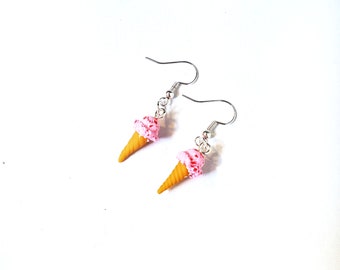 May include: A pair of silver dangle earrings featuring pink and white ice cream cones with a sprinkle design.