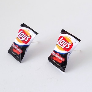 May include: A pair of black and white Lay's potato chip bag earrings. The bags are black with white text that reads "Lay's Masterpiece" and "Potato Chips".