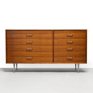 May include: A mid-century modern dresser with six drawers. The wooden dresser has a warm brown finish and silver-colored metal legs. Each drawer has a unique, curved handle.