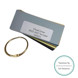 May include: A set of color swatches for cloud cover, labeled "Cloud Cover 2025-2027 In Color 165621". The swatches are arranged in a fan shape and held together with a gold ring. A white circle with a teal border contains the text "Handmade By KrisKustomKreations1 Kris Henderson".
