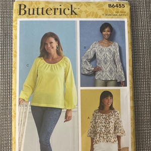 Puede incluir: Patrón de costura Butterick B6455 para blusas en tallas XSM-SML-MED. El sobre muestra tres variaciones: una blusa amarilla lisa de manga larga, una blusa con estampado de cachemira azul y blanco con mangas acampanadas y una blusa blanca con hojas.