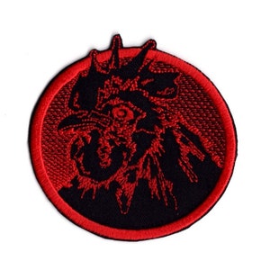 May include: Circular embroidered patch with a stylized rooster head in black and red. The rooster's head is centrally positioned, encircled by a red border. The patch is set against a white backdrop.
