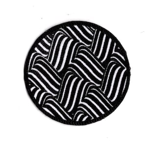 Op de afbeelding: Zwarte en witte gestreepte stoffen patch met een ronde vorm en een zwarte rand.