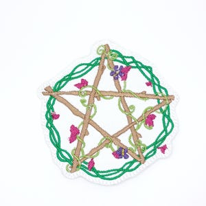 May include: Embroidered patch featuring a brown pentagram design with green vines and pink and purple flowers. The patch has a white border with a scalloped edge. The design is on a white background.