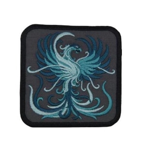 May include: A blue and white embroidered patch featuring a phoenix with intricate details. The patch is on a gray background with a black border.