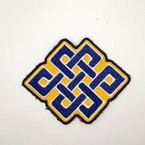 May include: An embroidered patch featuring a blue and yellow endless knot design. The knot is outlined in white thread against a bright yellow background, with a thick black border surrounding the entire shape of the square-like emblem.