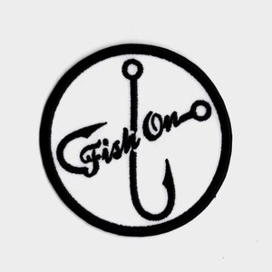 May include: Black and white embroidered patch with a circle around a fishing hook and the text "Fish On" in a cursive font.