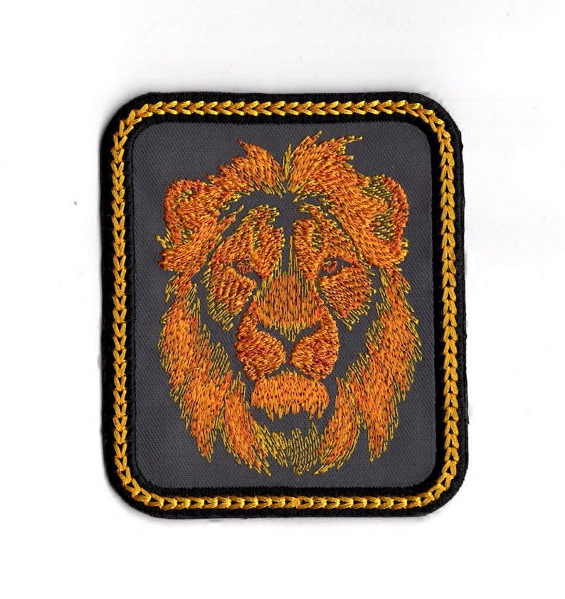 May include: A dark gray embroidered patch with a gold border featuring a lion's head with orange and yellow fur.