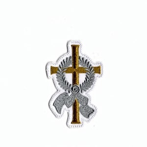 Op de afbeelding: Gouden kruis met een zilveren krans en strik, geborduurd op een witte stoffen patch.