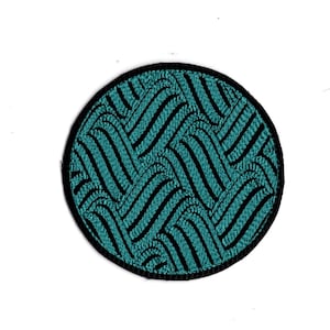 May include: A round, black and teal embroidered patch with a geometric pattern.
