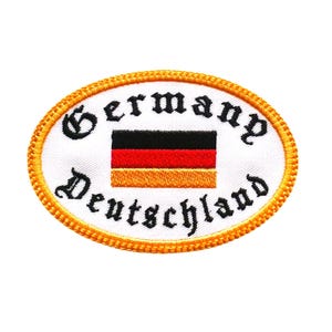 May include: A white oval patch with a yellow border. The patch has the words "Germany Deutschland" in black embroidery and a small embroidered German flag in the centre.