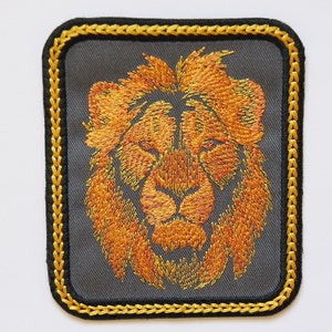 May include: Embroidered lion head patch with a gold outline on a gray background. The lion's mane is a vibrant orange color.