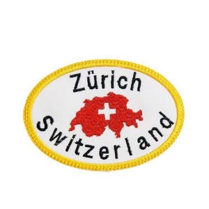 Könnte beinhalten: Gestickter Aufnäher mit einem weißen ovalen Mittelteil und einem gelben Rand. Der Aufnäher zeigt die Worte "Zürich Switzerland" in Schwarz, mit einer roten Schweizer Flaggen-Grafik in der Mitte.