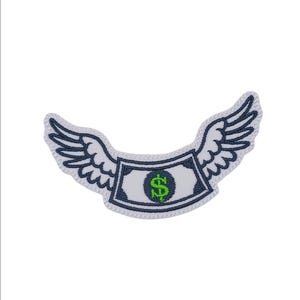 May include: Embroidered patch featuring a dollar bill with white wings and a navy blue border. The dollar bill has a green dollar sign in the center. The patch is designed to be ironed on or sewn onto fabric.