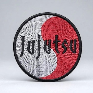May include: A circular embroidered patch featuring a yin-yang design split into silver and red sections. The word Jujutsu is stitched in black thread across the center of the patch, which is finished with a thick black stitched border edge.