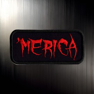 May include: Red embroidered patch with the word "'MERICA" in a stylized font on a black background.