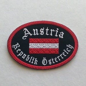 Embroidered Austria travel patch with red and white flag on black twill fabric, 3.5 by 2.5 inches