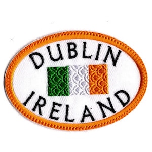 May include: An oval-shaped embroidered patch with a white background and an orange border. The text DUBLIN IRELAND is stitched in black, surrounding a small, textured tricolor flag of green, white, and orange in the center.