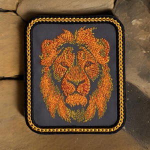 May include: Embroidered lion head patch with a gold border. The lion is orange and yellow with a gray background.