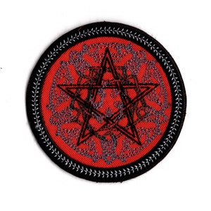 Peut inclure: Un écusson brodé rouge et noir avec une étoile à cinq branches au centre. L'étoile est entourée d'un motif circulaire de petites étoiles et d'autres formes géométriques.