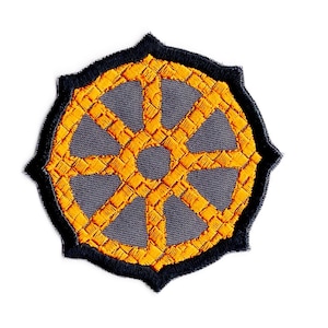 May include: A round, embroidered patch with a black outline and a yellow wheel design. The wheel has eight spokes and a central hub.
