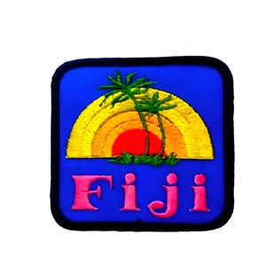 May include: A square embroidered patch with a blue background featuring a yellow and orange semi-circular sunset graphic, two green palm trees, and the word Fiji in pink lettering. The patch has a thick black border around the entire edge.