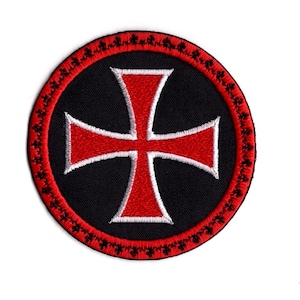 Peut inclure: Un patch circulaire noir avec une bordure rouge et noire, sur lequel est brodé une croix rouge avec un contour blanc.