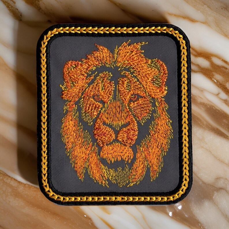 May include: A gray embroidered patch with a gold border featuring a lion's head with orange and yellow fur.