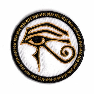 Op de afbeelding: Een ronde, zwart-gouden geborduurde patch met een witte achtergrond. De patch heeft een gestileerd oog van Horus-ontwerp.
