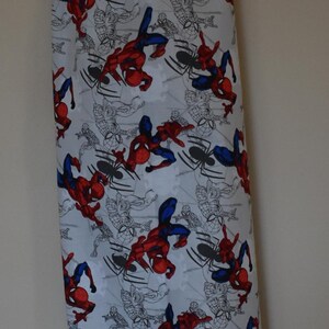 May include: A white reusable grocery bag with a blue drawstring and a pattern of red and blue Spiderman characters on a white background.