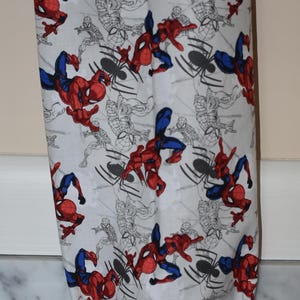 May include: White reusable grocery bag with a red and blue Spiderman pattern. The bag has a drawstring closure.