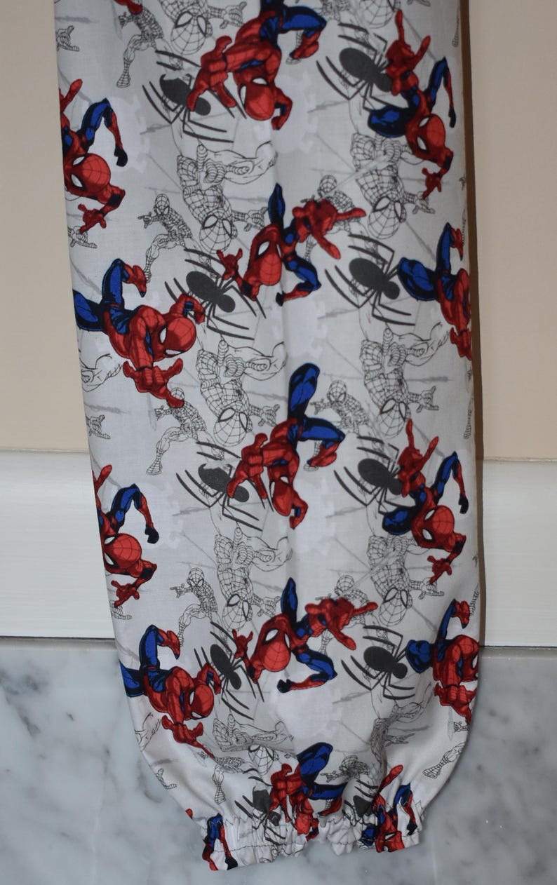 May include: White reusable grocery bag with a red and blue Spiderman pattern. The bag has a drawstring closure.