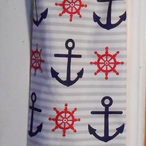 May include: A white and gray striped reusable grocery bag with a red and white anchor and steering wheel design. The bag has a red drawstring.