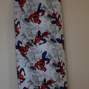 May include: A white reusable grocery bag with a blue drawstring and a pattern of red and blue Spiderman characters on a white background.