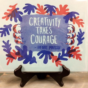 May include: A blue and red print with a white background. The print features a quote by Henri Matisse: "Creativity takes courage".