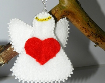 May include: White felt angel ornament with a red felt heart and a gold halo. The angel is hanging from a white beaded string.