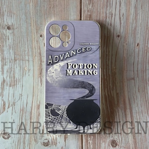May include: A phone case with a design featuring the words "Advanced Potion Making" in white, with a black cauldron and swirling steam. The case has a gray and purple background with a metallic texture and a cutout for the camera.