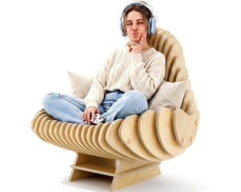 May include: A light-colored wooden lounge chair constructed from a series of vertical, curved plywood slats that form a shell-like seat. The chair features a low, sturdy base and includes two light beige square cushions placed on the interior sides.