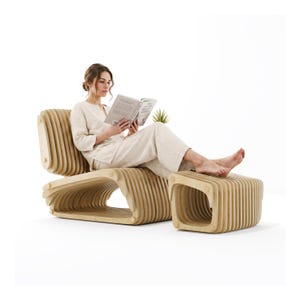 May include: A light-colored wooden lounge chair and matching ottoman constructed from a series of vertical, parallel slats. The chair features a low-profile, curved frame with rounded edges, creating a hollow, layered structure for seating.