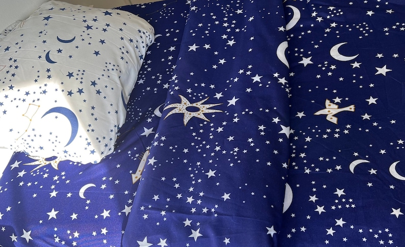 K&ouml;nnte beinhalten: Ein blaues und wei&szlig;es Bettw&auml;sche-Set mit einem Sternen- und Halbmondmuster. Die Bettw&auml;sche ist aus weichem, bequemem Stoff gefertigt und perfekt, um jedem Schlafzimmer einen Hauch von Verspieltheit zu verleihen.