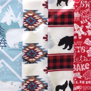 Könnte beinhalten: Vier Stoffmuster mit verschiedenen Mustern. Das erste Muster ist hellblau mit einem weißen Eisbären und einer Bergkette. Das zweite Muster ist weiß mit einem braunen, roten und blauen geometrischen Muster. Das dritte Muster ist weiß mit einem roten und schwarzen Karomuster. Das vierte Muster ist rot mit weißem Text, der "Sweet Ginger Bread Man" und anderen weihnachtlichen Texten sagt.