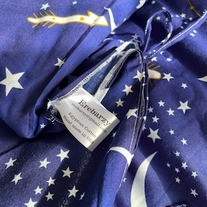 K&ouml;nnte beinhalten: Nahaufnahme eines blauen Stoffes mit wei&szlig;en Sternen und Halbmonden. Der Stoff hat ein wei&szlig;es Etikett mit der Aufschrift "Eirebarzy eirebarzy@gmail.com Egyptian Cotton Hand made in USA".