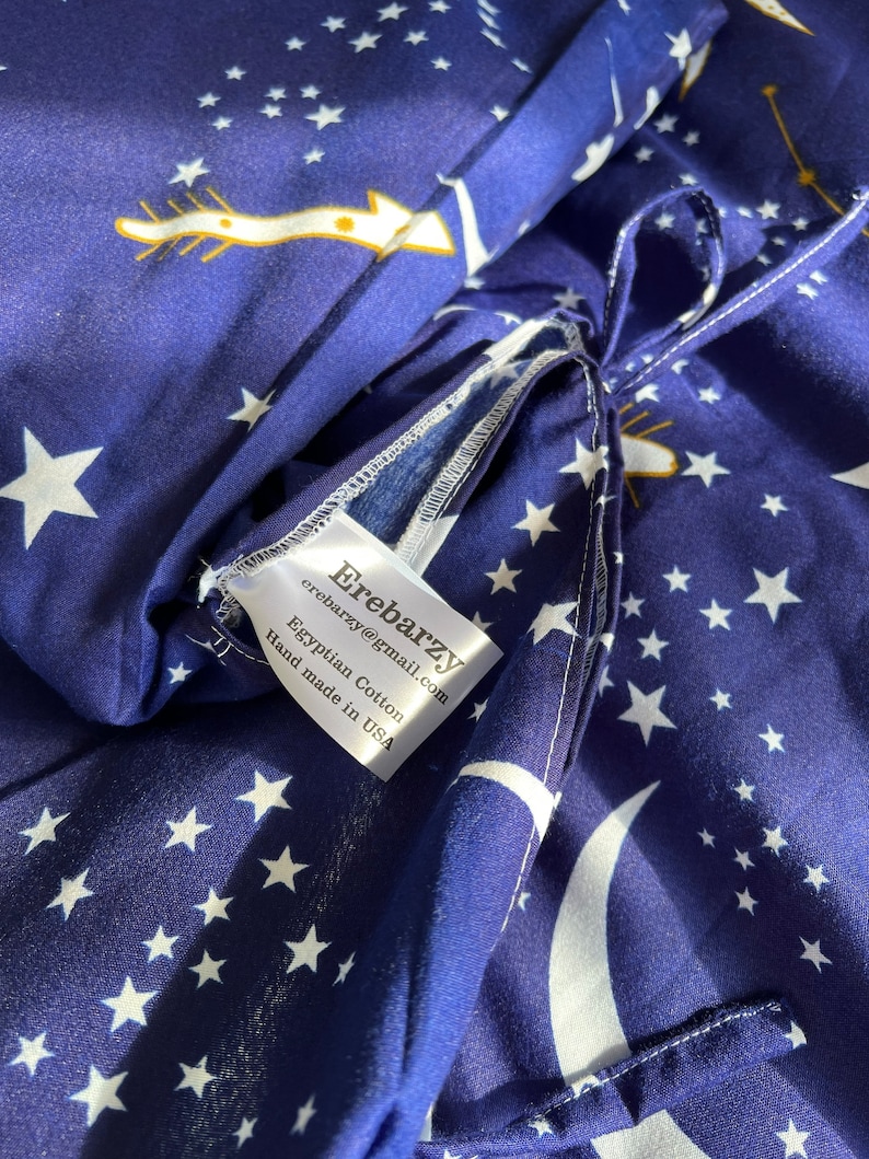 K&ouml;nnte beinhalten: Nahaufnahme eines blauen Stoffes mit wei&szlig;en Sternen und Halbmonden. Der Stoff hat ein wei&szlig;es Etikett mit der Aufschrift "Eirebarzy eirebarzy@gmail.com Egyptian Cotton Hand made in USA".