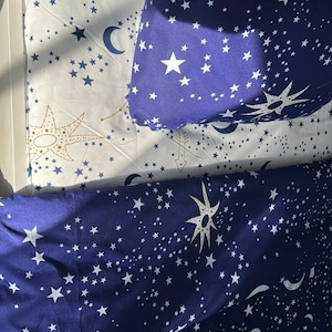 K&ouml;nnte beinhalten: Ein blaues und wei&szlig;es Bettw&auml;sche-Set mit einem Sternen- und Mondmuster. Die Bettw&auml;sche ist aus weichem, bequemem Stoff gefertigt und perfekt, um jedem Schlafzimmer einen Hauch von Verspieltheit zu verleihen.