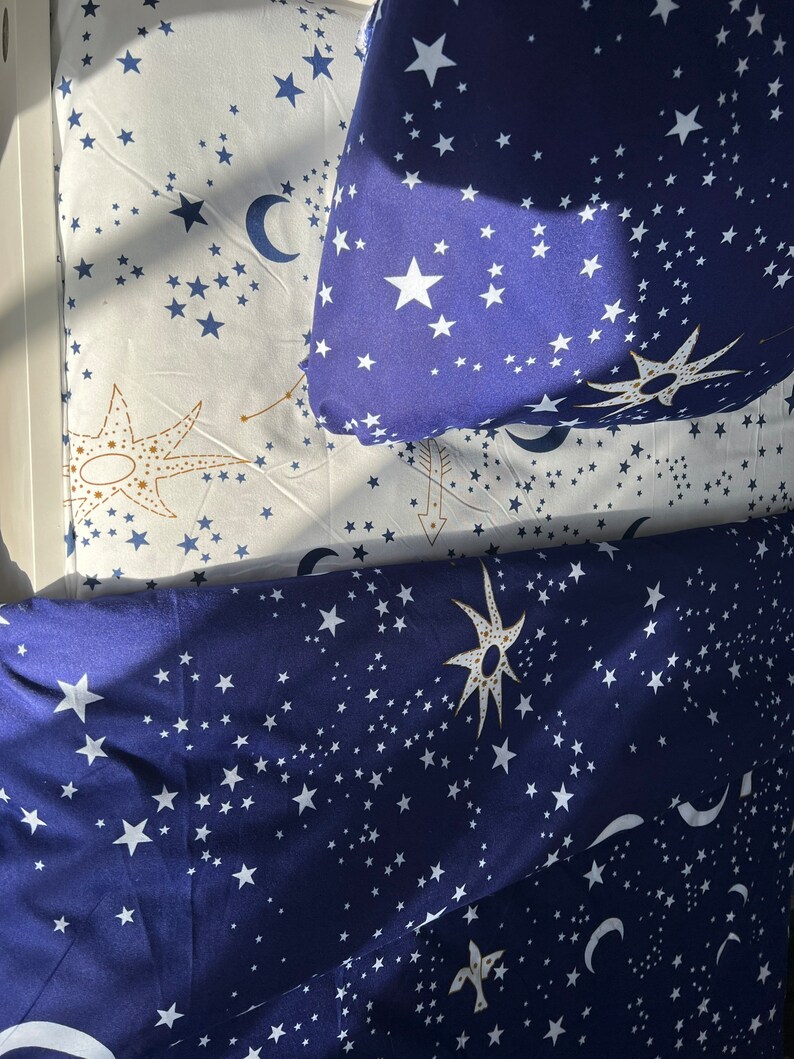 K&ouml;nnte beinhalten: Ein blaues und wei&szlig;es Bettw&auml;sche-Set mit einem Sternen- und Mondmuster. Die Bettw&auml;sche ist aus weichem, bequemem Stoff gefertigt und perfekt, um jedem Schlafzimmer einen Hauch von Verspieltheit zu verleihen.
